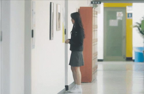 woman standing in hallway with cellphone at door
