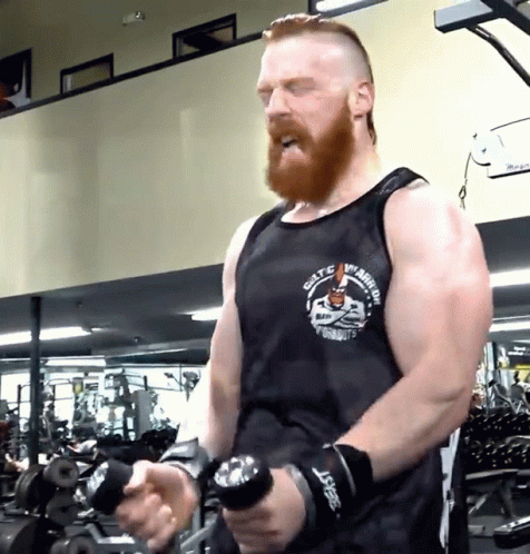 man with beard holding soing with one hand in a gym