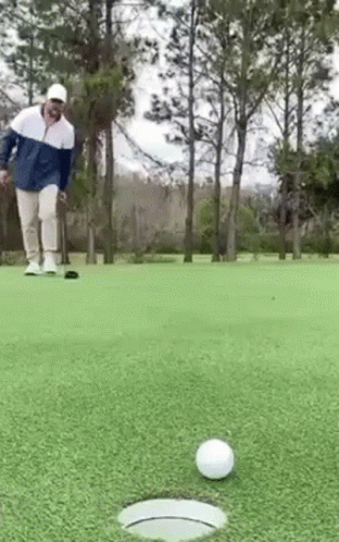 a man in a white coat on golf putting a ball on the green