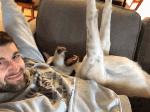 a man laying down next to his dog on a couch