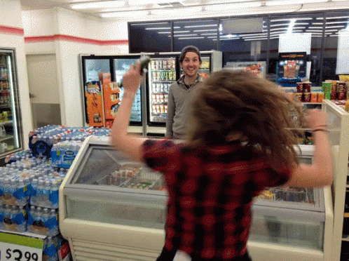 a young lady is waving in the grocery store