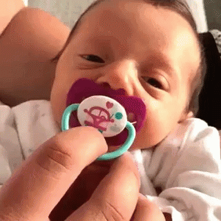 a person holds onto a dummy and the baby is wearing a pacifier