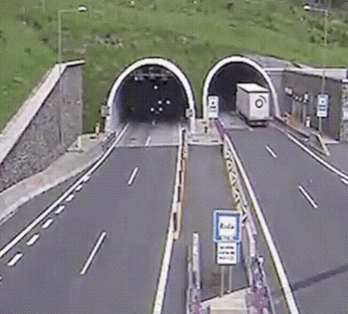 a highway going into a tunnel that has green grass growing on the side