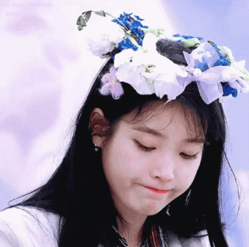 a girl in a white shirt has flowers on her head