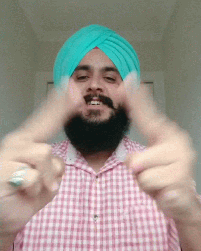 a bearded man with a turban and pointing fingers towards the camera