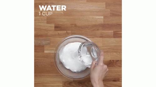 a hand pouring water into a cup that is blue and white