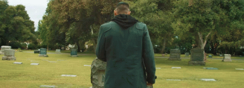 a man in an old fashion coat walking around a graveyard