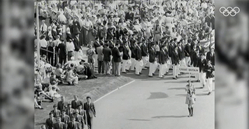 an olympic ceremony with spectators standing and laying in the background