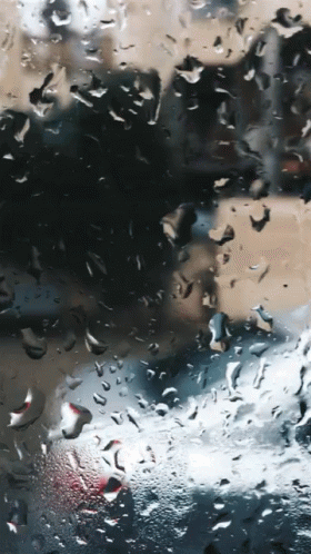 the image shows the reflection of people on a bus window with rain falling over them