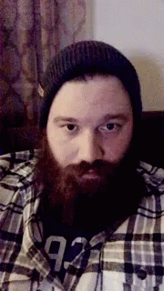 man with long beard wearing plaid shirt in room
