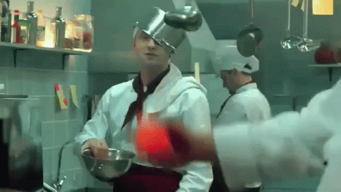two chefs with glasses and hats cooking food in a kitchen