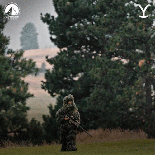 the person in the camouflage suit is holding an umbrella