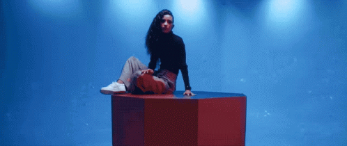 a woman in a black top and blue jeans on a large object