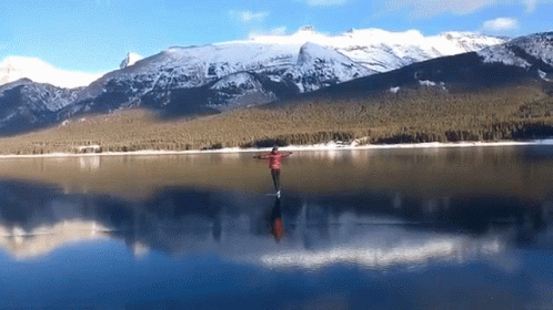 a lake in the middle of mountains with a person near it