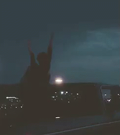 a woman raises her hands in the air, near a plane