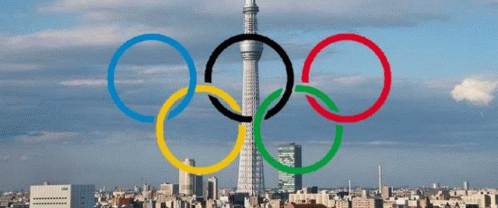 four colorful olympic rings with tokyo in the background