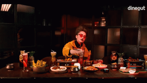 a person wearing sunglasses at a table filled with food