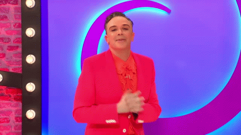 a woman in a purple suit and pink shirt standing next to a neon sign