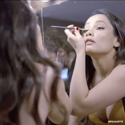 a woman in the reflection of a mirror getting her make - up done