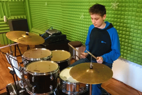 a boy that is playing a drums set on a blue floor