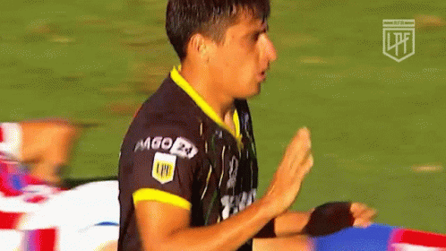 an asian man on a soccer field wearing black and blue