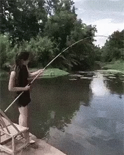 a lady standing on a dock while she holds onto her fishing rod