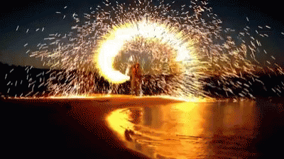 a bright firework is seen as a person stands in the water