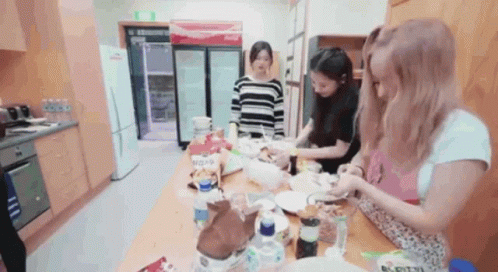 a woman in black and white shirt and some girls making cookies