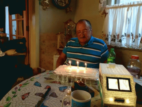 a man is sitting at a table with candles and a cake
