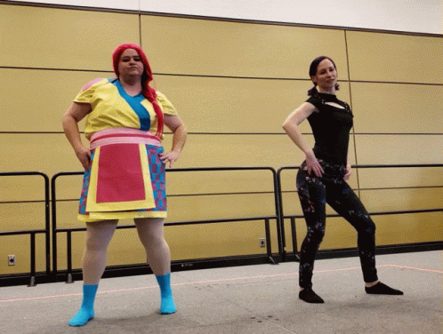 two women in costumes are standing in front of a wall