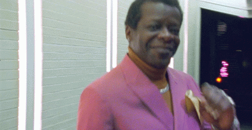 a man wearing a pink jacket holds a pair of scissors