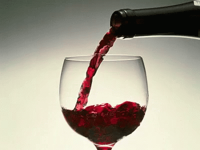 a close up of wine pouring from a bottle into a glass