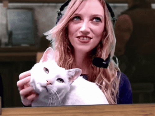a woman wearing headphones is holding a cat