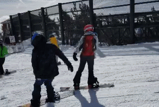 a group of people on snowboards near a fence