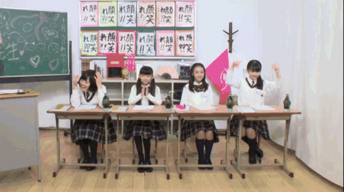 the girls sit on the desk with books in their hand