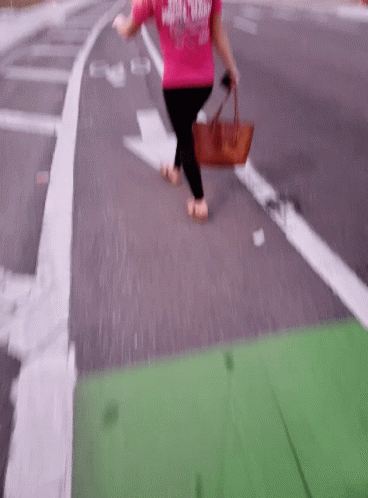 the woman in the purple shirt is walking across the street