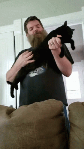 a man holding a black cat in his hands