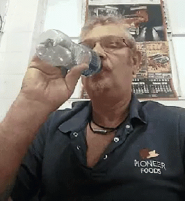 a man drinking a glass of water while sitting
