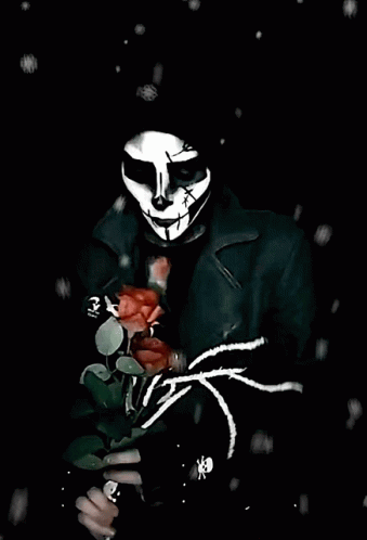 a man wearing an evil mask and holding a rose in his hand