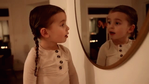 two small girls looking at their own reflection in a mirror
