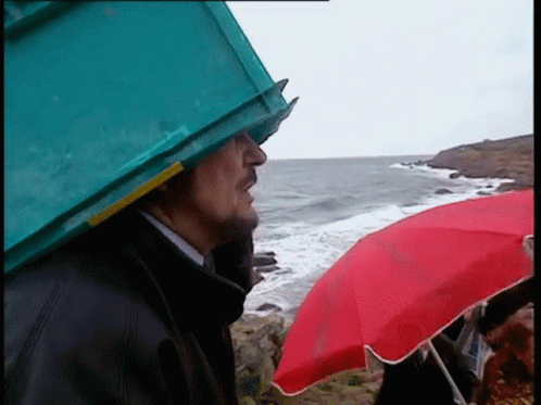 the man is holding a blue umbrella near the ocean