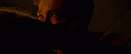 a man sitting in a dark room in the dark with his hand on his face