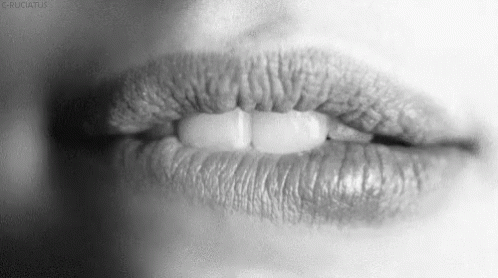 black and white pograph of woman lip with pill on it