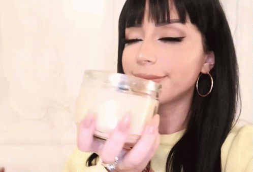 woman with white makeup and piercings drinking a glass