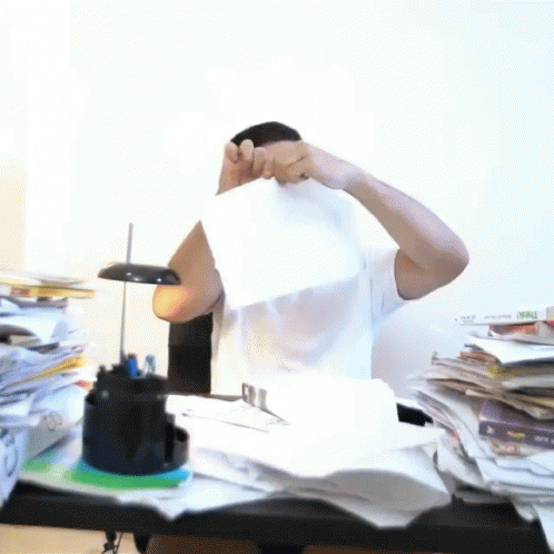 a person is covering their face next to a stack of paperwork