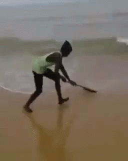 a man on the beach sweeping the sand and water