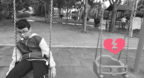 two children in a playground on swings with their hands near them