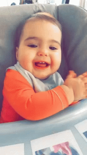 a baby smiles while sitting in a chair