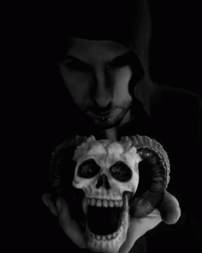 a man holds up a small human skull