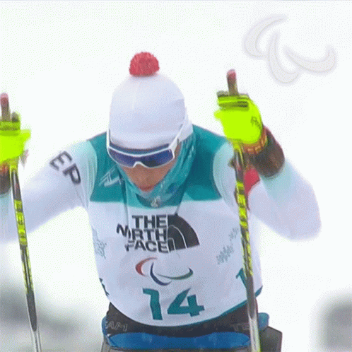 a skier wearing a hat and holding his poles while standing in the snow
